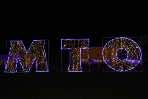 Brightly lit letters "M," "T," and "O" adorned with blue and white lights against a dark night sky.