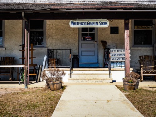 Front view of Whitesbog General Store with a closed sign, steps leading up, and planters on either side.