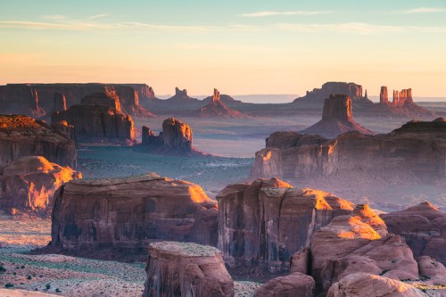 A stunning desert landscape at sunset, featuring towering rock formations and a colorful sky in Monument Valley.