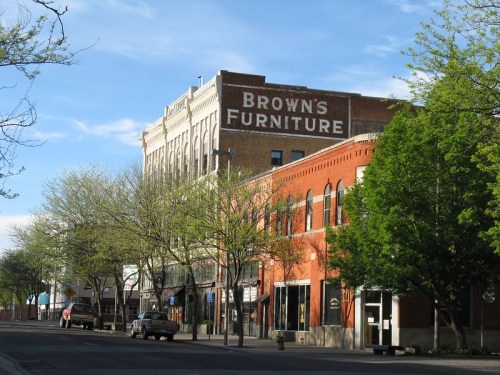 Historic buildings line a street, featuring a prominent sign for "Brown's Furniture" and lush green trees.