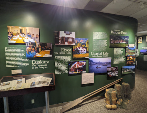 Exhibit wall featuring Basque culture, with photos and text about language, family life, and coastal living.