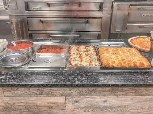 A display of various Italian dishes, including pasta, lasagna, and pizza, in a restaurant setting.