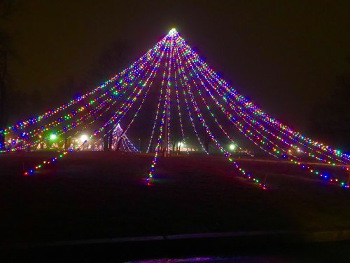 A colorful display of Christmas lights arranged in a tree shape, glowing against a dark night sky.
