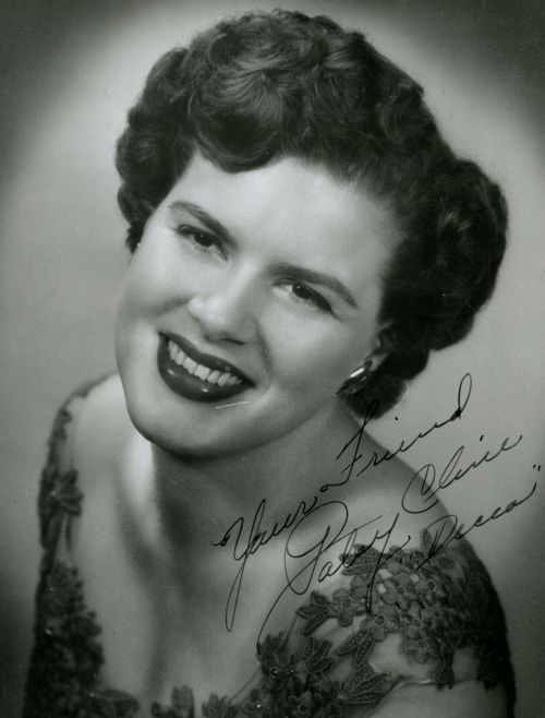 A smiling woman with curly hair, wearing a floral dress, with a handwritten note signed "Your Friend, Patsy Cline."