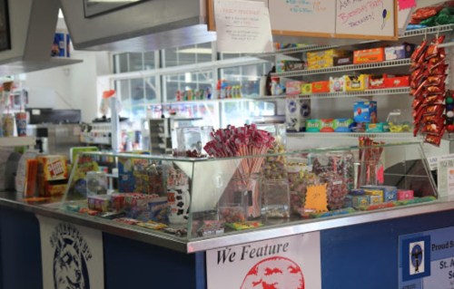 A colorful convenience store counter filled with candy, snacks, and various products on display.