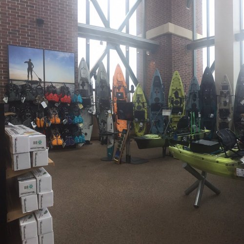 A store interior showcasing various kayaks and paddleboards displayed on walls and stands.