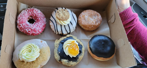A box of assorted donuts, featuring various toppings like sprinkles, icing, and cream, arranged neatly.