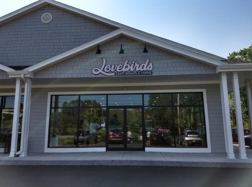 Exterior of Lovebirds Craft Donuts & Coffee shop, featuring a modern design and large glass windows.