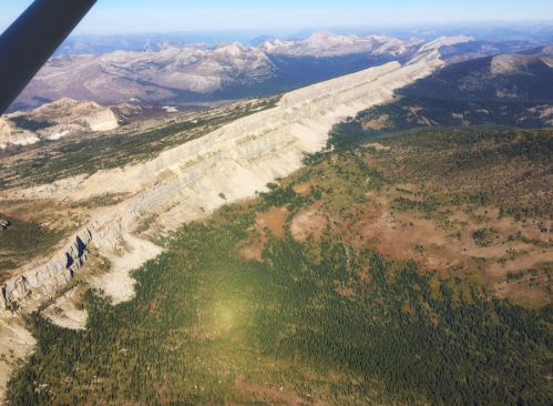 Aerial view of a rugged mountain landscape with a prominent, flat-topped ridge and surrounding forested areas.