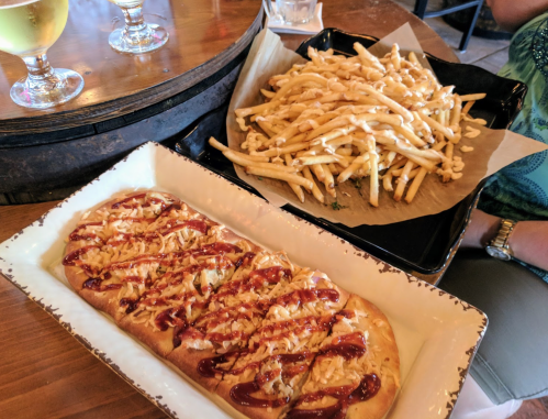 A flatbread topped with barbecue sauce and cheese, served alongside a large portion of crispy fries.