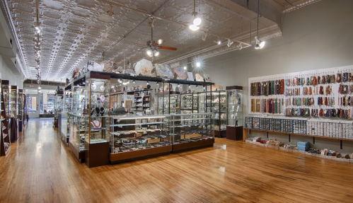 A spacious store interior featuring display cases filled with various items and shelves lined with products.