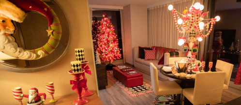 A festive living room decorated for Christmas, featuring a tree, Santa decor, and colorful holiday accents.