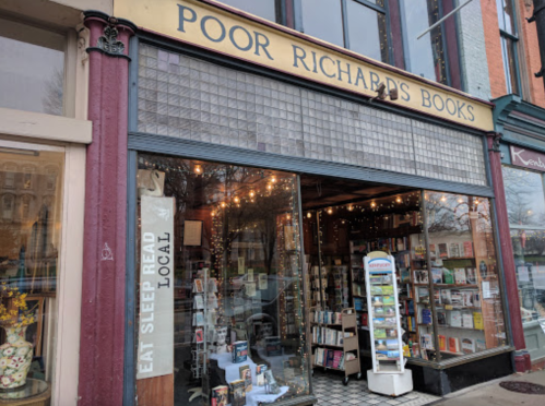 A cozy bookstore with a sign reading "Poor Richard's Books," featuring a window display and bookshelves inside.