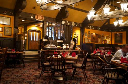 Cozy restaurant interior with wooden tables, red napkins, and warm lighting, featuring vintage decor and a welcoming atmosphere.