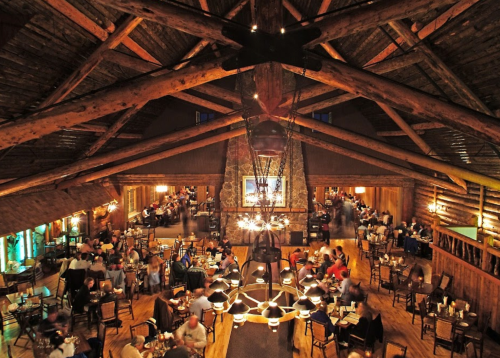 A cozy restaurant interior with wooden beams, warm lighting, and diners enjoying their meals in a rustic setting.