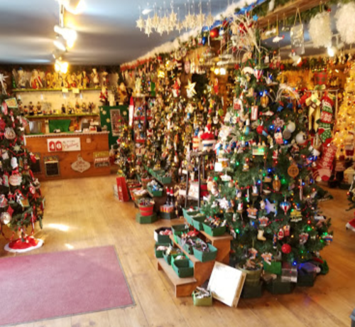 A festive shop filled with decorated Christmas trees, ornaments, and holiday decorations, creating a cheerful atmosphere.