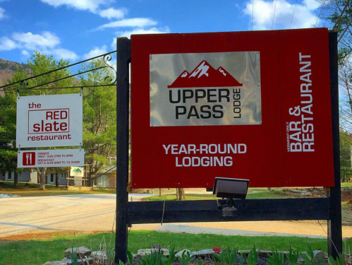 Sign for Upper Pass Lodge and Red Slate Restaurant, featuring information about lodging and dining options.