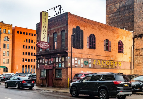 Historic Jacoby's restaurant with a brick exterior and signage, surrounded by parked cars and urban buildings.