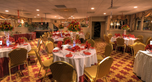 Elegant dining room set for an event, featuring round tables with red napkins and floral centerpieces.