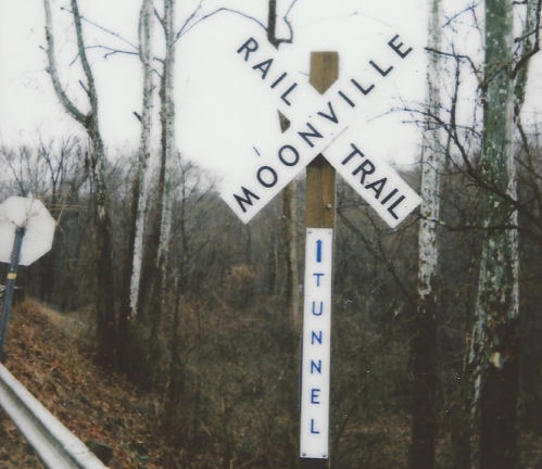 Signpost for the Moonville Rail Trail, indicating a tunnel ahead, surrounded by bare trees.