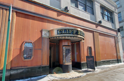 Exterior of the Cliff Bell's building, featuring a vintage marquee and a sidewalk sign, with snow on the ground.