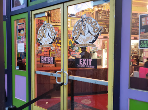 Colorful entrance doors of a doughnut shop with "Enter" and "Exit" signs, featuring a playful logo.