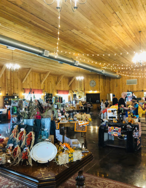 A rustic interior of a market with wooden walls, string lights, and various vendor displays featuring seasonal decor.