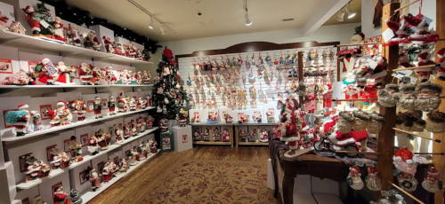 A festive store display filled with various Santa figurines and Christmas ornaments on shelves and tables.
