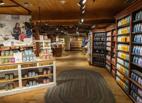 A cozy store interior with shelves of candles and home goods, featuring warm wood accents and soft lighting.