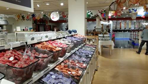 A colorful display of various soaps in baskets at a store, with a person browsing in the background.