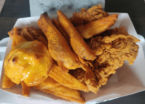 A tray of crispy fried chicken pieces and golden-brown potato wedges.