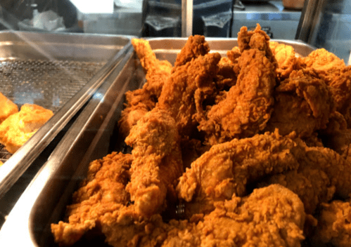 A close-up of a tray filled with crispy, golden-brown fried chicken pieces.