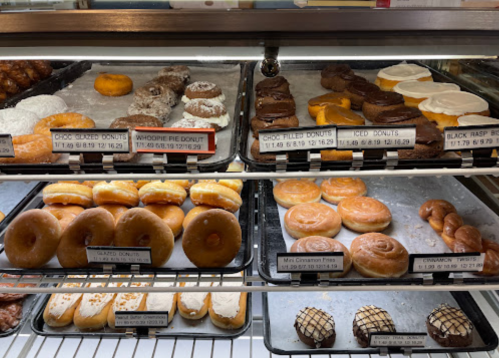 A display case filled with various donuts, including glazed, chocolate, and filled options, neatly arranged on trays.