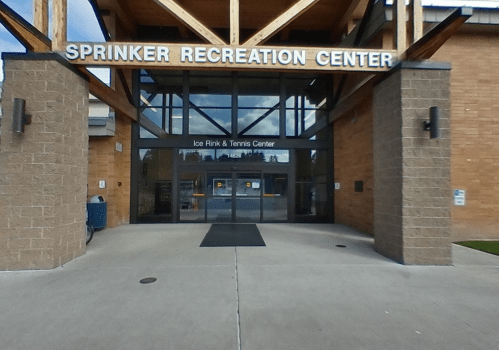 Entrance of Sprinker Recreation Center featuring glass doors and a sign for the Ice Rink & Tennis Center.