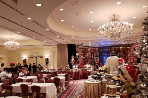 Elegant banquet hall decorated for a festive event, featuring chandeliers, tables, and a holiday-themed backdrop.