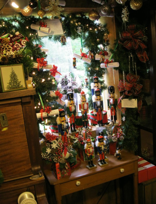 A festive window display featuring nutcracker figurines, holiday decorations, and a wreath adorned with lights.