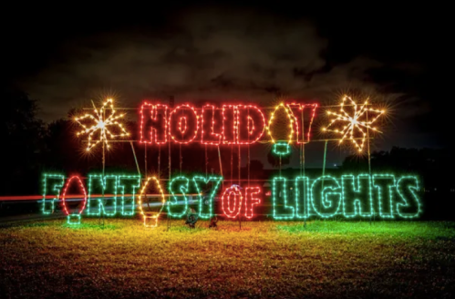 Colorful holiday lights spell out "Holiday Fantasy of Lights" against a dark night sky.