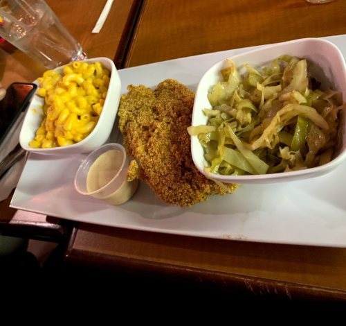 A plate with fried chicken, macaroni and cheese, and sautéed cabbage in small bowls.