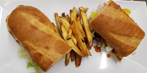 Two sandwiches with lettuce on a plate, accompanied by a side of golden-brown fries.
