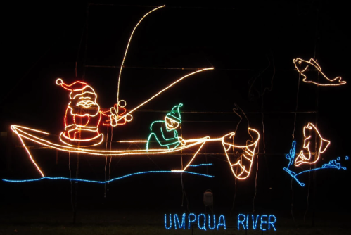 Colorful holiday lights depicting Santa and an elf fishing on a boat with fish jumping in the water, labeled "Umpqua River."