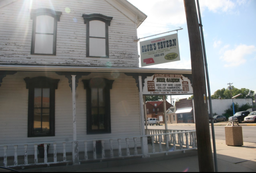Exterior of Glue's Tavern, a historic building with a sign, located on a sunny street corner.
