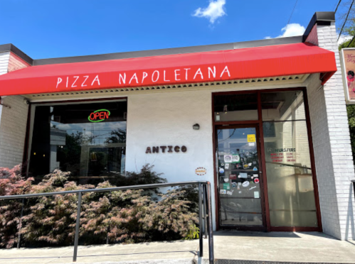 Exterior of Antico Pizza Napoletana with a red awning, "OPEN" sign, and clear blue sky in the background.