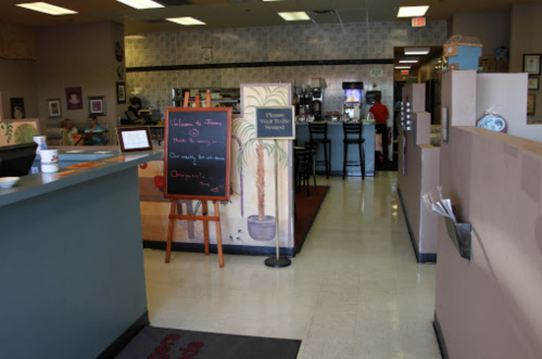 Interior of a cozy café with a welcoming sign, seating area, and a counter in the background.