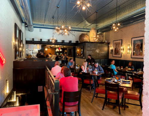 A cozy restaurant interior with diners at tables, modern lighting, and a warm atmosphere.