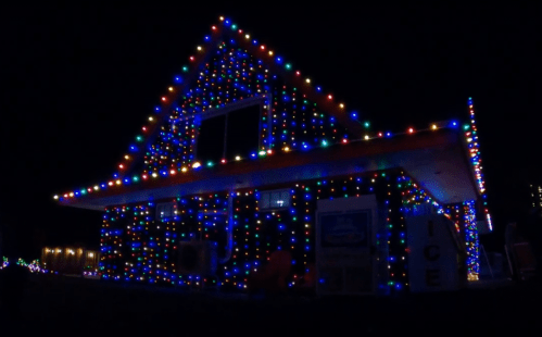 A house covered in colorful Christmas lights, glowing brightly against the night sky.