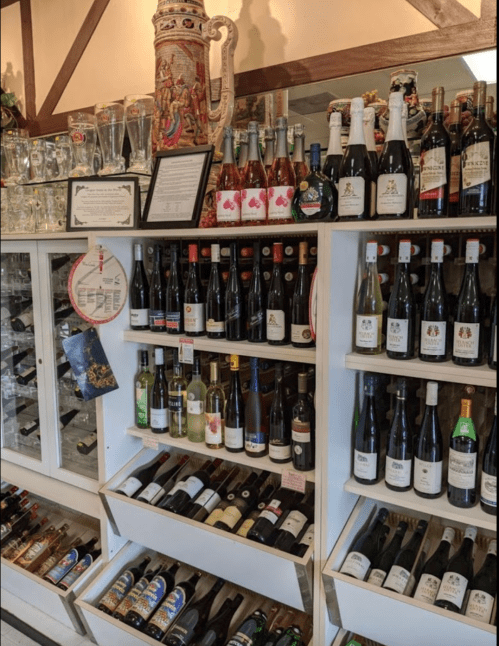 A display of various bottles of wine and spirits on shelves, with decorative glassware in the background.