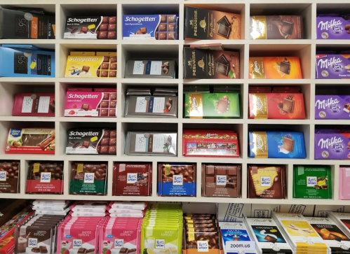 A display of various chocolate brands and types arranged neatly on shelves.