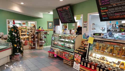 A cozy store interior with a Christmas tree, display cases of food, and colorful menus on the walls.