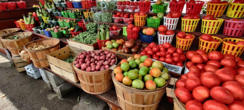 A vibrant display of fresh vegetables and fruits in colorful baskets at a market.
