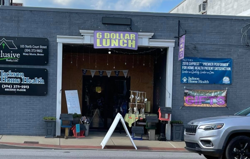 A storefront with a sign reading "6 DOLLAR LUNCH" and banners for Jackson Home Health and local gifts.